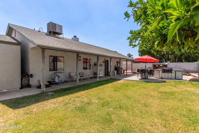 rear view of house with exterior kitchen, a patio, central AC unit, stucco siding, and a chimney