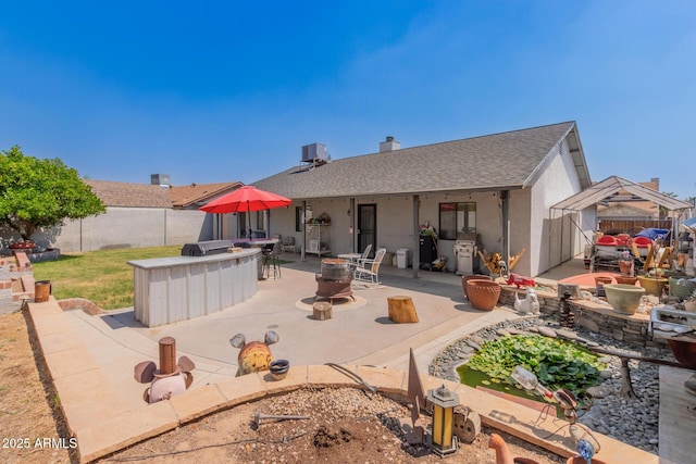 rear view of house with a fenced backyard, a patio area, roof with shingles, and stucco siding