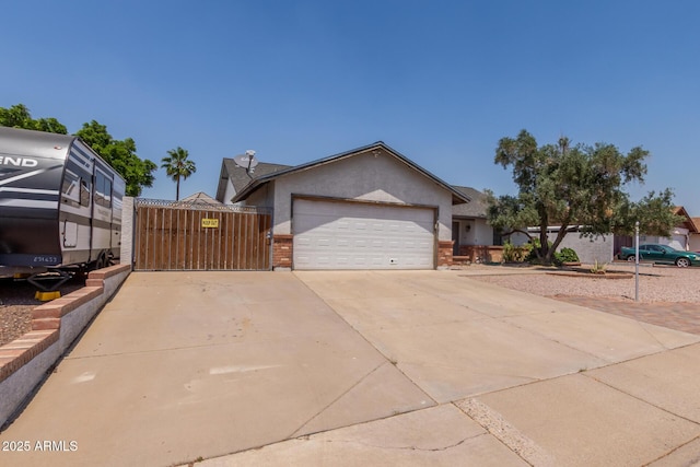 view of front of property featuring an attached garage, concrete driveway, brick siding, a gate, and stucco siding