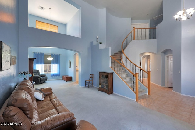 carpeted living room with visible vents, arched walkways, baseboards, stairway, and a chandelier