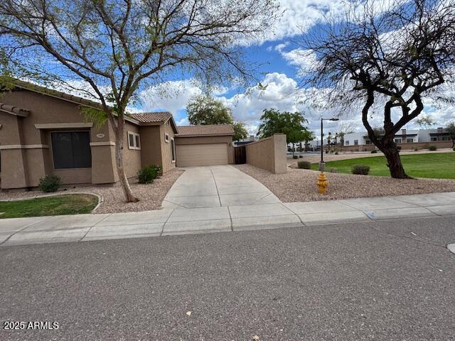 view of front facade featuring a tiled roof, an attached garage, driveway, and stucco siding