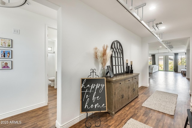 hall featuring visible vents, baseboards, and dark wood-type flooring