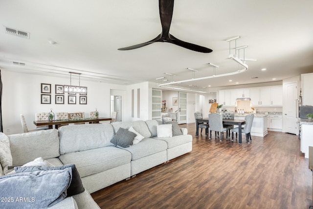 living area featuring dark wood-type flooring, visible vents, and a ceiling fan