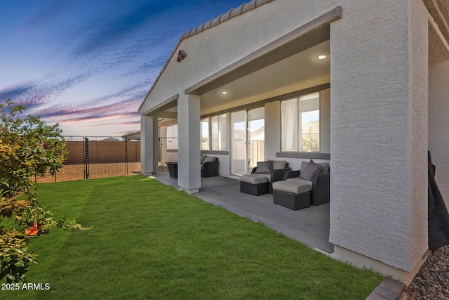 back of property with a patio, outdoor lounge area, fence, a lawn, and stucco siding