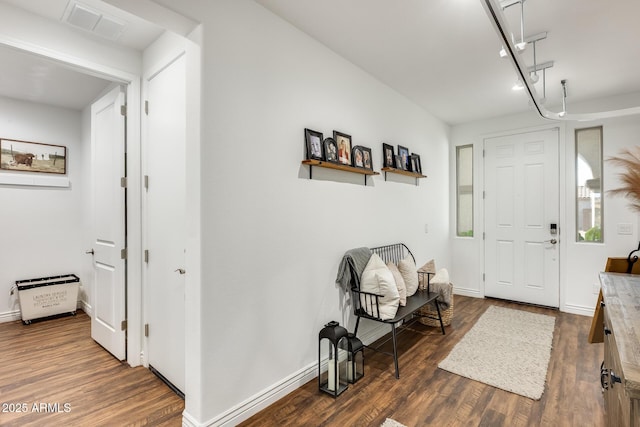 foyer entrance with rail lighting, visible vents, dark wood finished floors, and baseboards