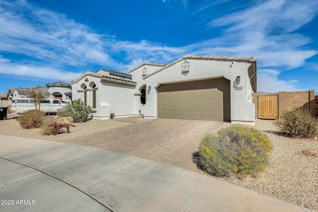 mediterranean / spanish home featuring a garage, decorative driveway, a tile roof, and stucco siding