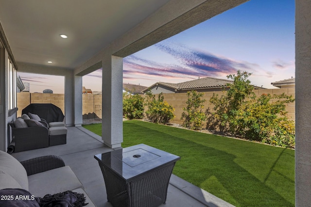 patio terrace at dusk with a fenced backyard, a lawn, and area for grilling