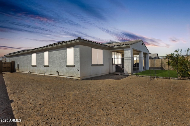 view of property exterior with a gate, fence, a tiled roof, and stucco siding