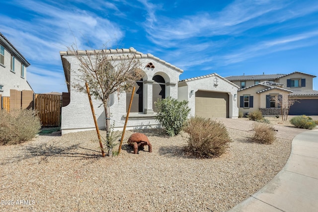 mediterranean / spanish-style house featuring a garage, a tile roof, fence, driveway, and stucco siding