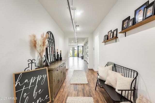 hallway with dark wood-style flooring, visible vents, and baseboards