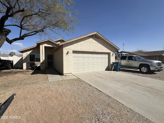 ranch-style house featuring concrete driveway, an attached garage, fence, and stucco siding