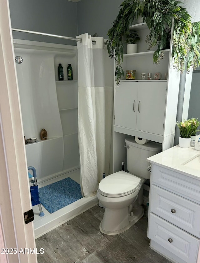 full bathroom with vanity, a shower stall, toilet, and wood finished floors