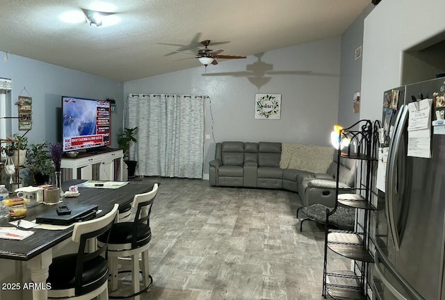 living room with a textured ceiling, wood finished floors, ceiling fan, and vaulted ceiling