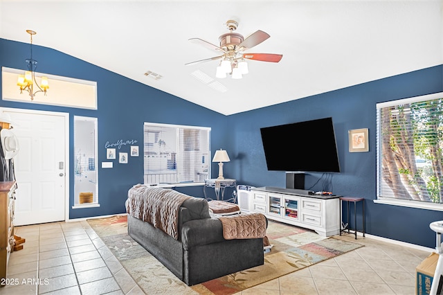 tiled living room featuring lofted ceiling and ceiling fan with notable chandelier