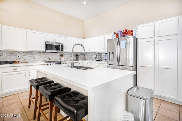 kitchen featuring sink, a breakfast bar area, white cabinetry, a center island with sink, and appliances with stainless steel finishes