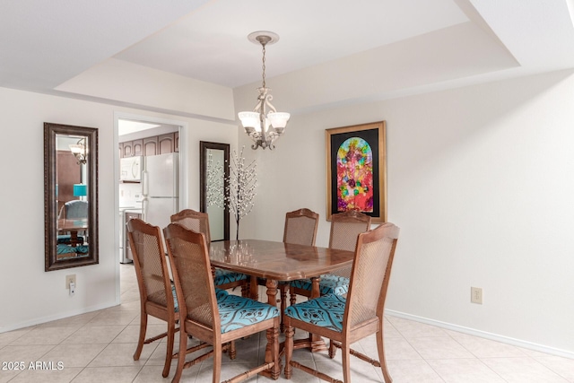 tiled dining space featuring a notable chandelier and a tray ceiling