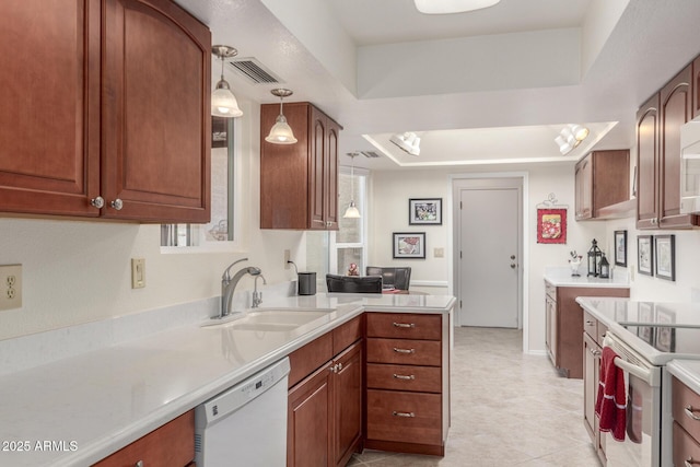 kitchen with white appliances, decorative light fixtures, sink, and a tray ceiling