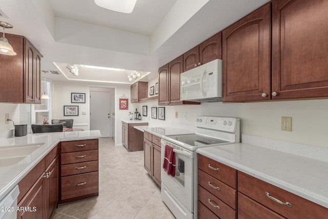 kitchen with sink, white appliances, light tile patterned floors, a tray ceiling, and pendant lighting