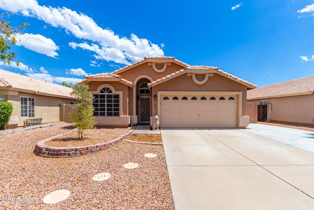 view of front of home featuring driveway, an attached garage, a tile roof, and stucco siding