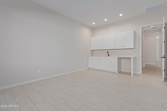 interior space featuring light hardwood / wood-style flooring, sink, and white cabinets