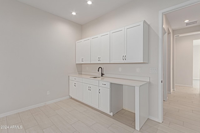 kitchen with light hardwood / wood-style floors, sink, and white cabinets