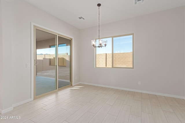 empty room with a notable chandelier and light hardwood / wood-style floors