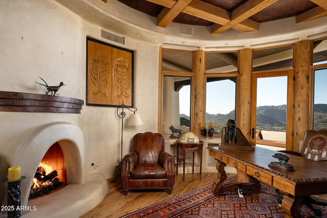 sitting room with wood-type flooring, a mountain view, coffered ceiling, and beam ceiling