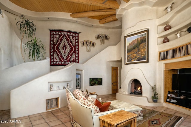 tiled living room featuring wood ceiling, a towering ceiling, and beamed ceiling