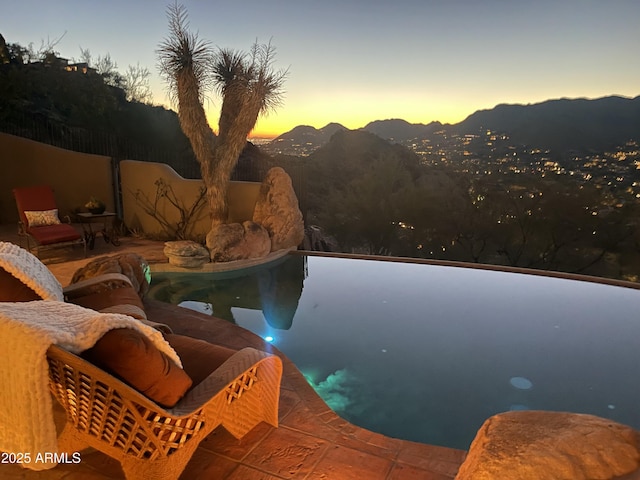 pool at dusk featuring a mountain view and a patio area