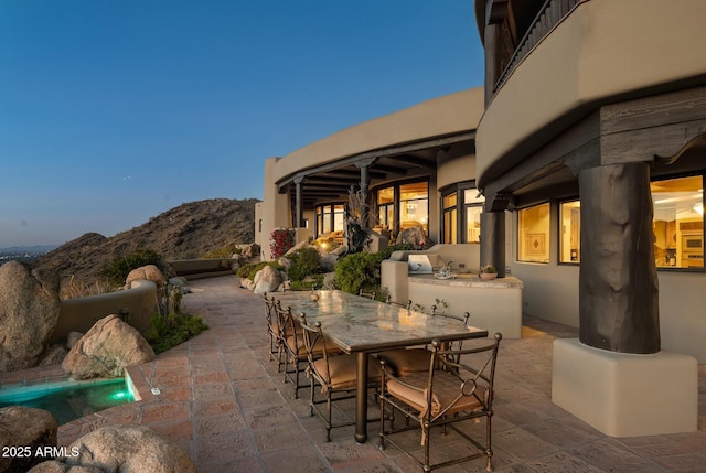 patio terrace at dusk with exterior kitchen and a mountain view