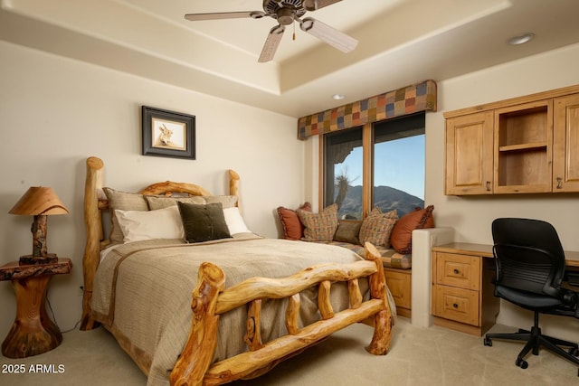 carpeted bedroom with ceiling fan and a tray ceiling