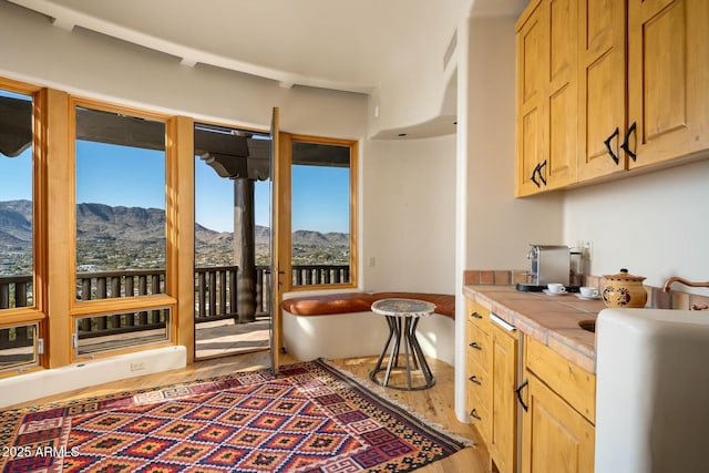 kitchen with hardwood / wood-style floors, a mountain view, tile counters, and light brown cabinetry