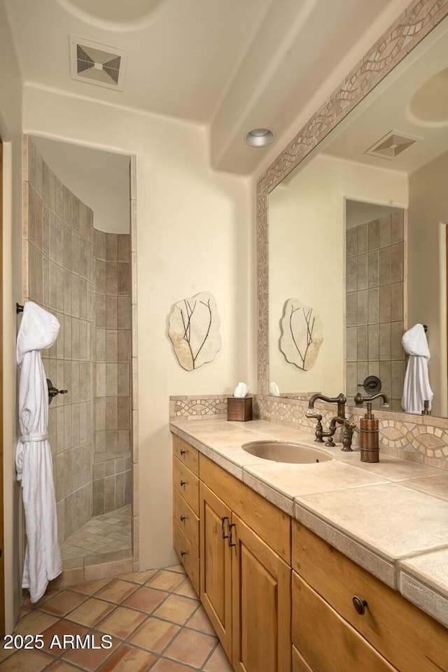 bathroom featuring tile patterned flooring, vanity, and a tile shower