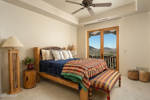 bedroom featuring ceiling fan, carpet floors, a mountain view, access to outside, and a raised ceiling