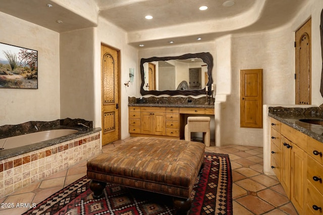 bathroom with tiled tub, vanity, and tile patterned floors