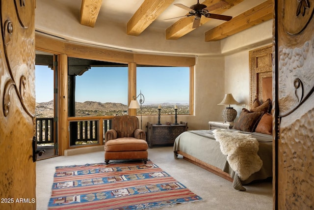 living area with a mountain view, beam ceiling, light colored carpet, and ceiling fan