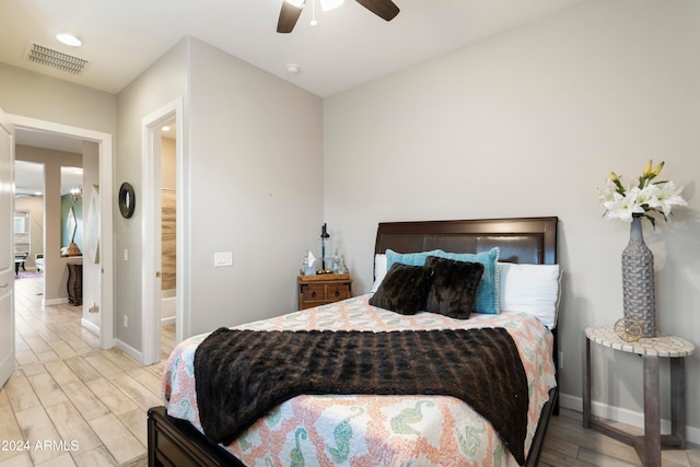 bedroom featuring light hardwood / wood-style floors, ceiling fan, and ensuite bath