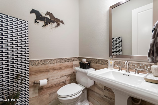 bathroom featuring toilet, tile walls, and sink