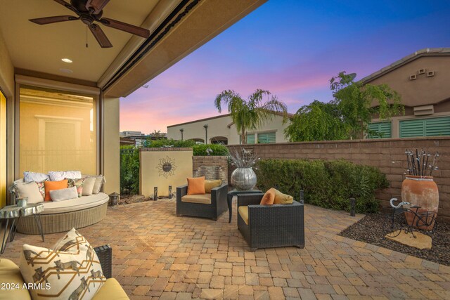 patio terrace at dusk featuring ceiling fan and an outdoor living space