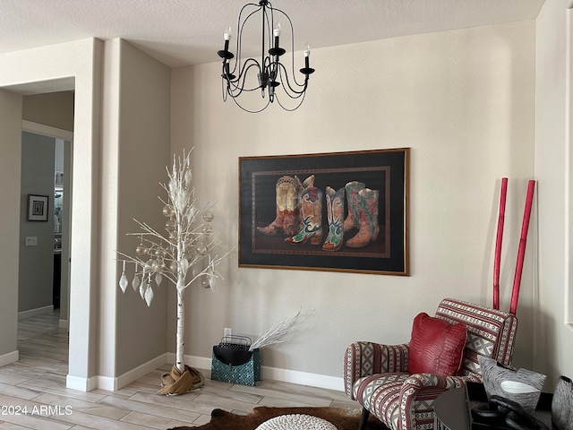 sitting room featuring light hardwood / wood-style floors, a textured ceiling, and an inviting chandelier