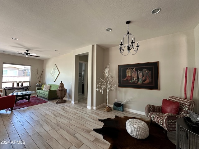 interior space with a textured ceiling, light hardwood / wood-style floors, and ceiling fan with notable chandelier