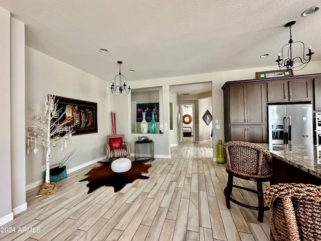 dining space featuring light hardwood / wood-style floors, a chandelier, and a textured ceiling