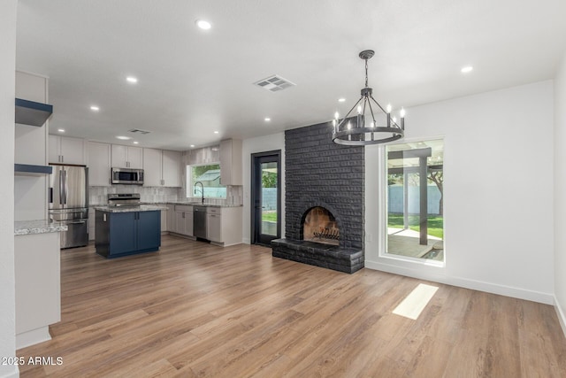 8602 N 42nd Dr, Phoenix, AZ 85051 - unfurnished living room with a chandelier, a brick fireplace, light wood-style floors, and recessed lighting