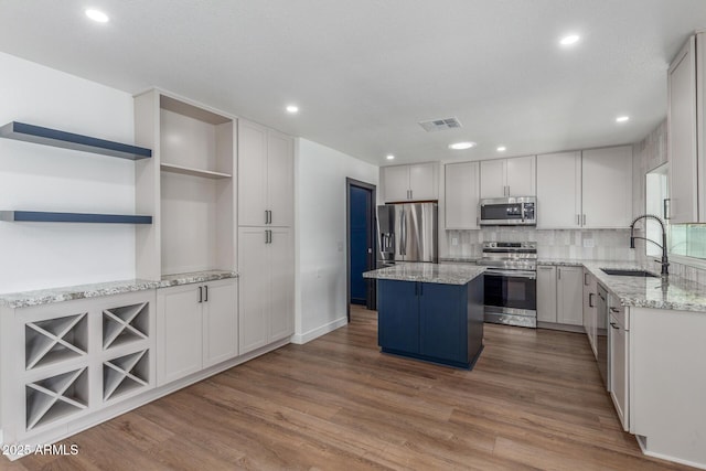 8602 N 42nd Dr, Phoenix, AZ 85051 - kitchen featuring stainless steel appliances, open shelves, a kitchen island, wood finished floors, and light stone countertops