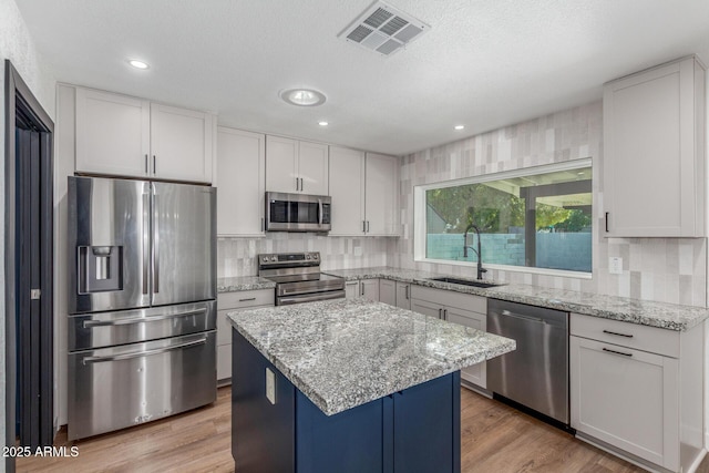 8602 N 42nd Dr, Phoenix, AZ 85051 - kitchen featuring stainless steel appliances, decorative backsplash, a center island, light stone countertops, and white cabinets