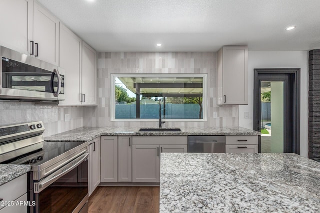 8602 N 42nd Dr, Phoenix, AZ 85051 - kitchen featuring stainless steel appliances, wood finished floors, light stone counters, tasteful backsplash, and a textured ceiling