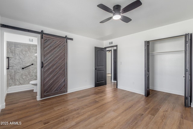 8602 N 42nd Dr, Phoenix, AZ 85051 - unfurnished bedroom featuring a closet, wood finished floors, a barn door, ensuite bath, and a ceiling fan
