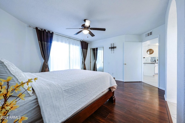 bedroom with a textured ceiling, dark hardwood / wood-style flooring, and ceiling fan