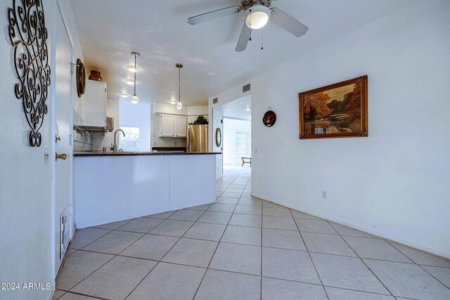 kitchen with light tile patterned flooring, white cabinets, decorative light fixtures, ceiling fan, and stainless steel fridge