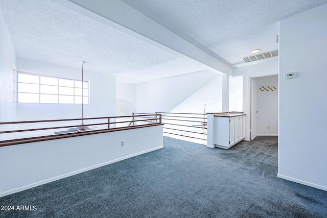 carpeted empty room with beam ceiling and a textured ceiling